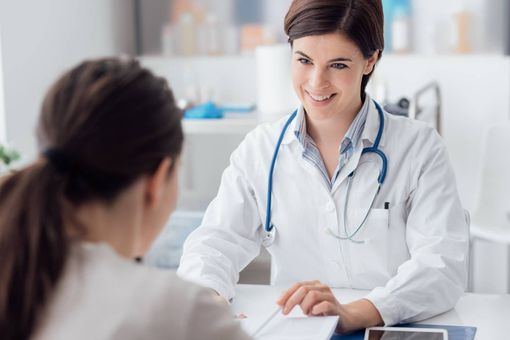 Doctor smiling across desk with patient in a bright clinic office
