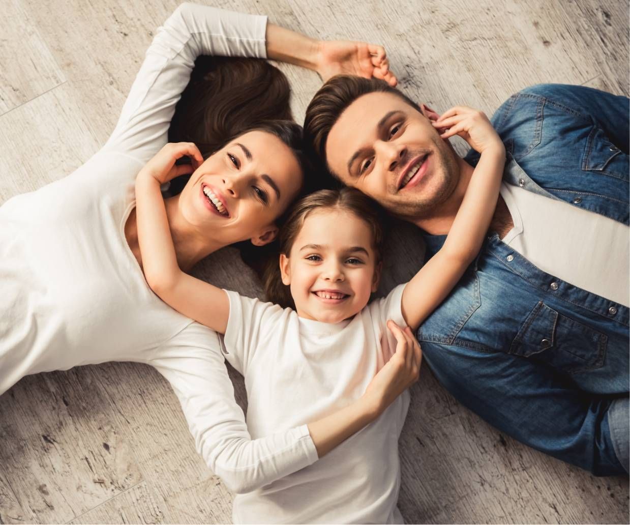 Family lying on a carpet, smiling and hugging each other in a cozy family moment