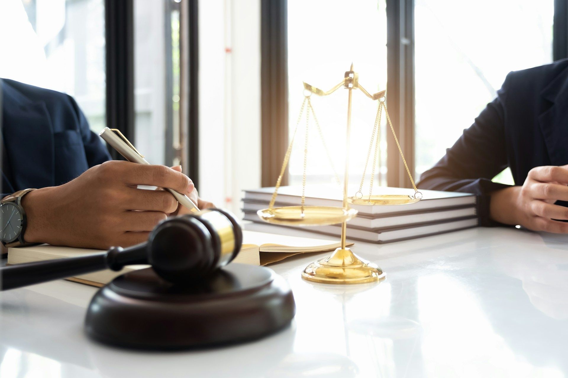 Lawyers at a table with gavel, scales of justice, and documents in a lit office.