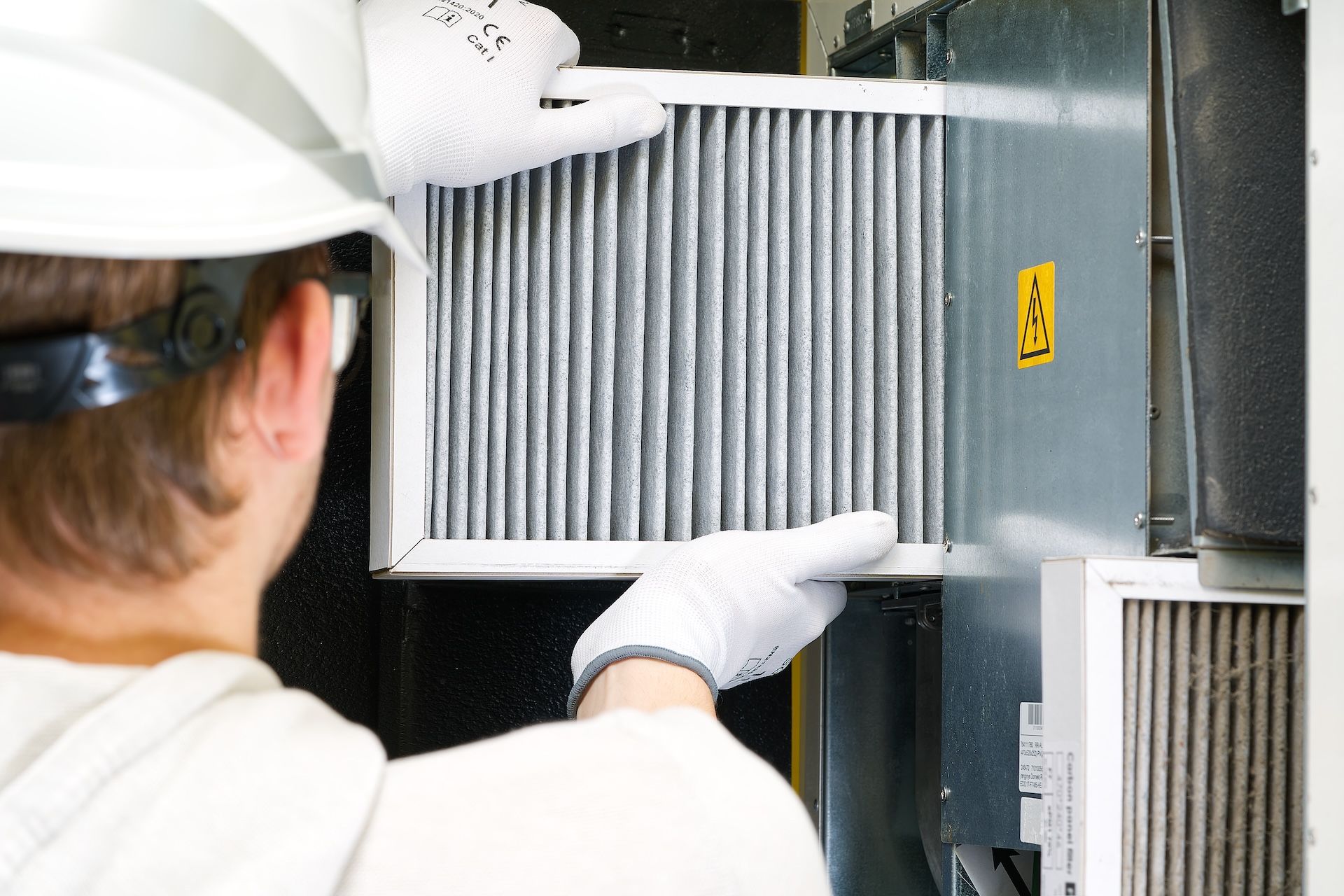 Technician replacing the HVAC air filter indoors