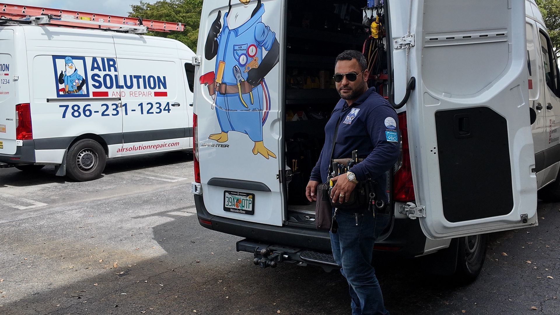 Man standing beside an open white service van with a colorful air solution logo in a parking lot