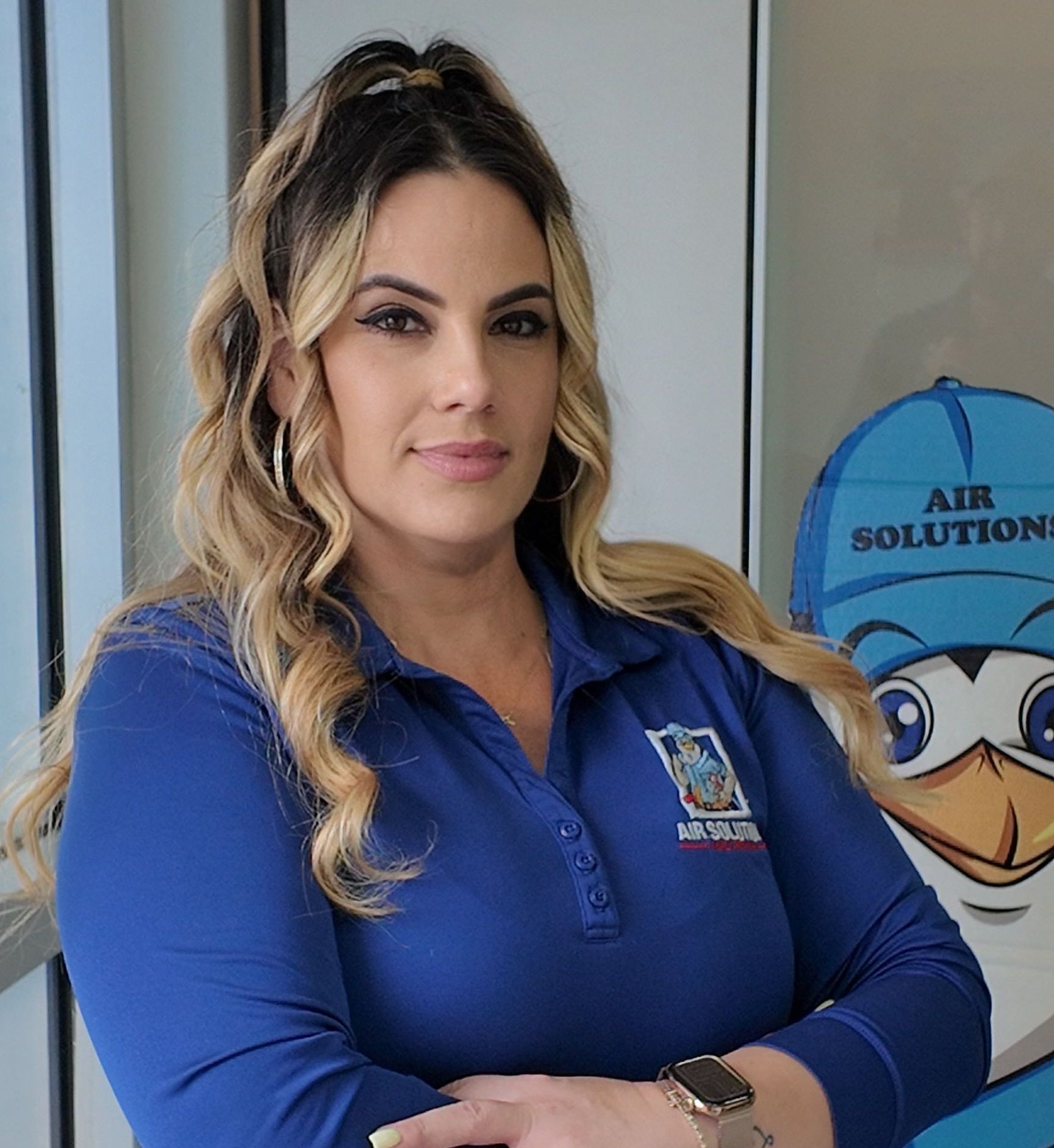 Woman in blue polo shirt standing indoors beside an Air Solutions sign