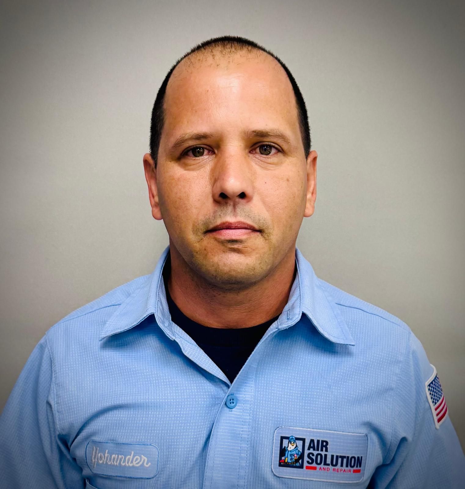 Man in a light blue work shirt with an Air Solution logo, standing against a gray background.