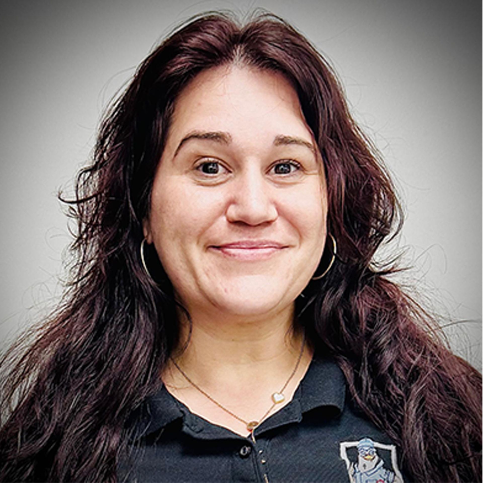 Portrait of a smiling person with long dark hair against a gray background