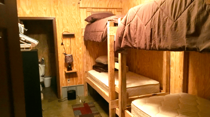 Wood-paneled bunk room with two bunk beds, a small sink, and a narrow walkway