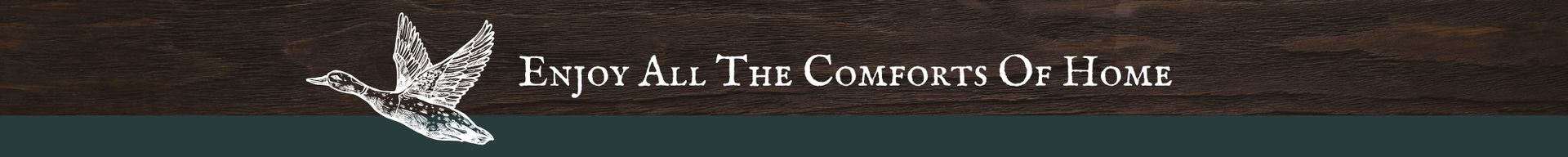 Banner with white eagle and text “Enjoy All The Comforts Of Home” on a brown wood background