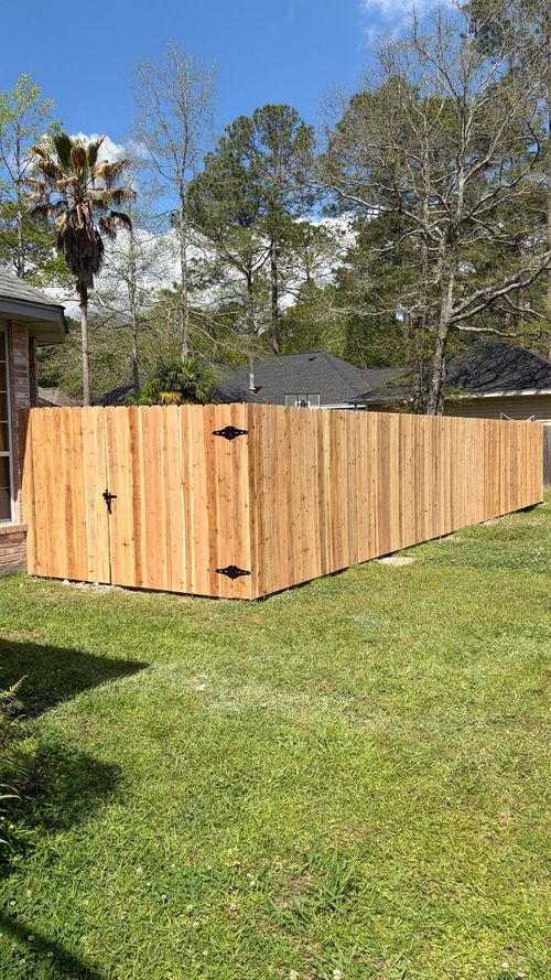 Wooden fenced enclosure in a grassy backyard under a clear blue sky