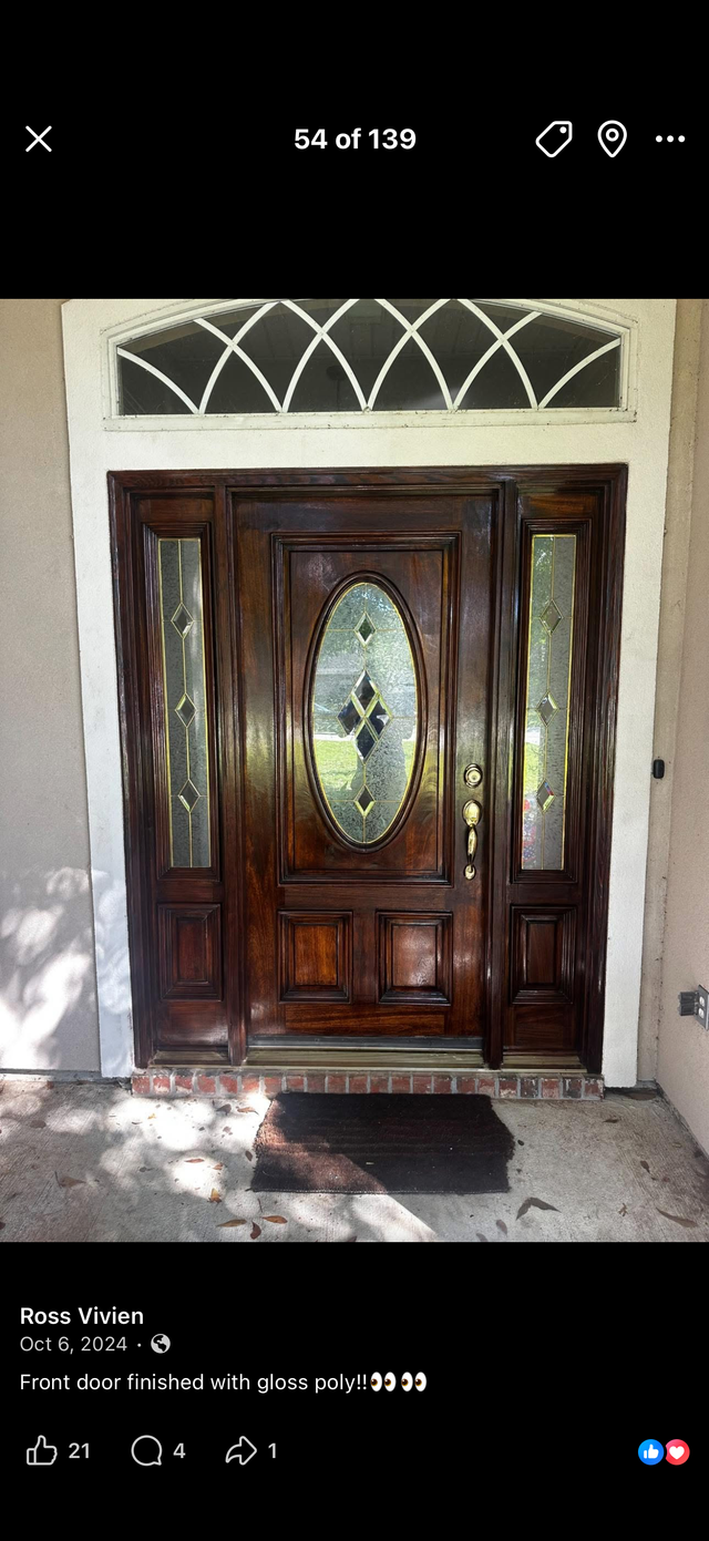 Wooden front door with oval glass panel and decorative transom, framed by beige stucco walls.