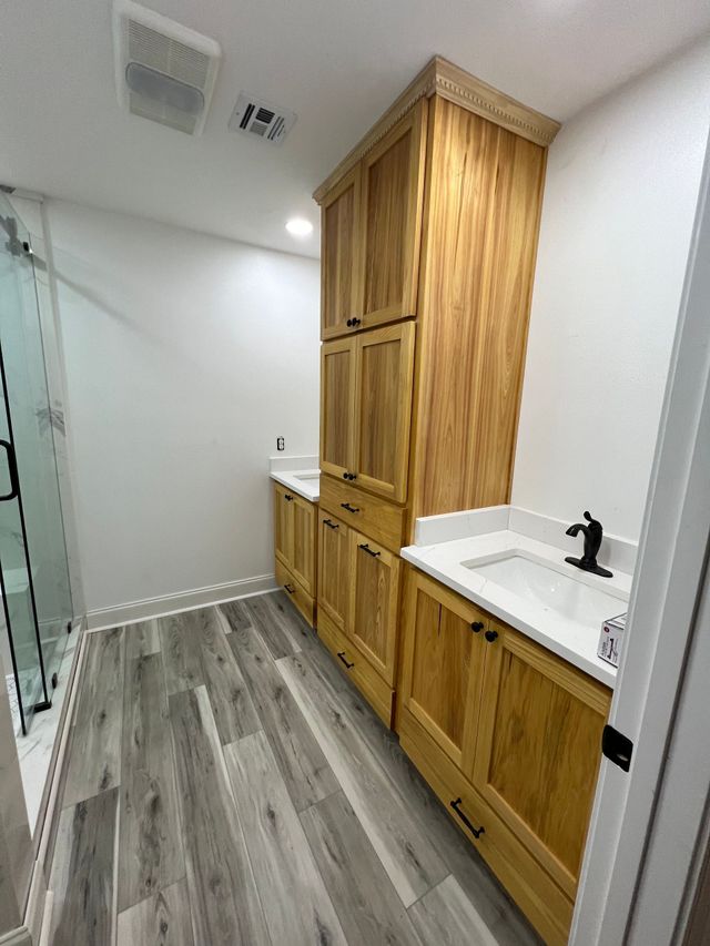 Narrow laundry room with wood cabinets, white countertop, and gray wood-look flooring