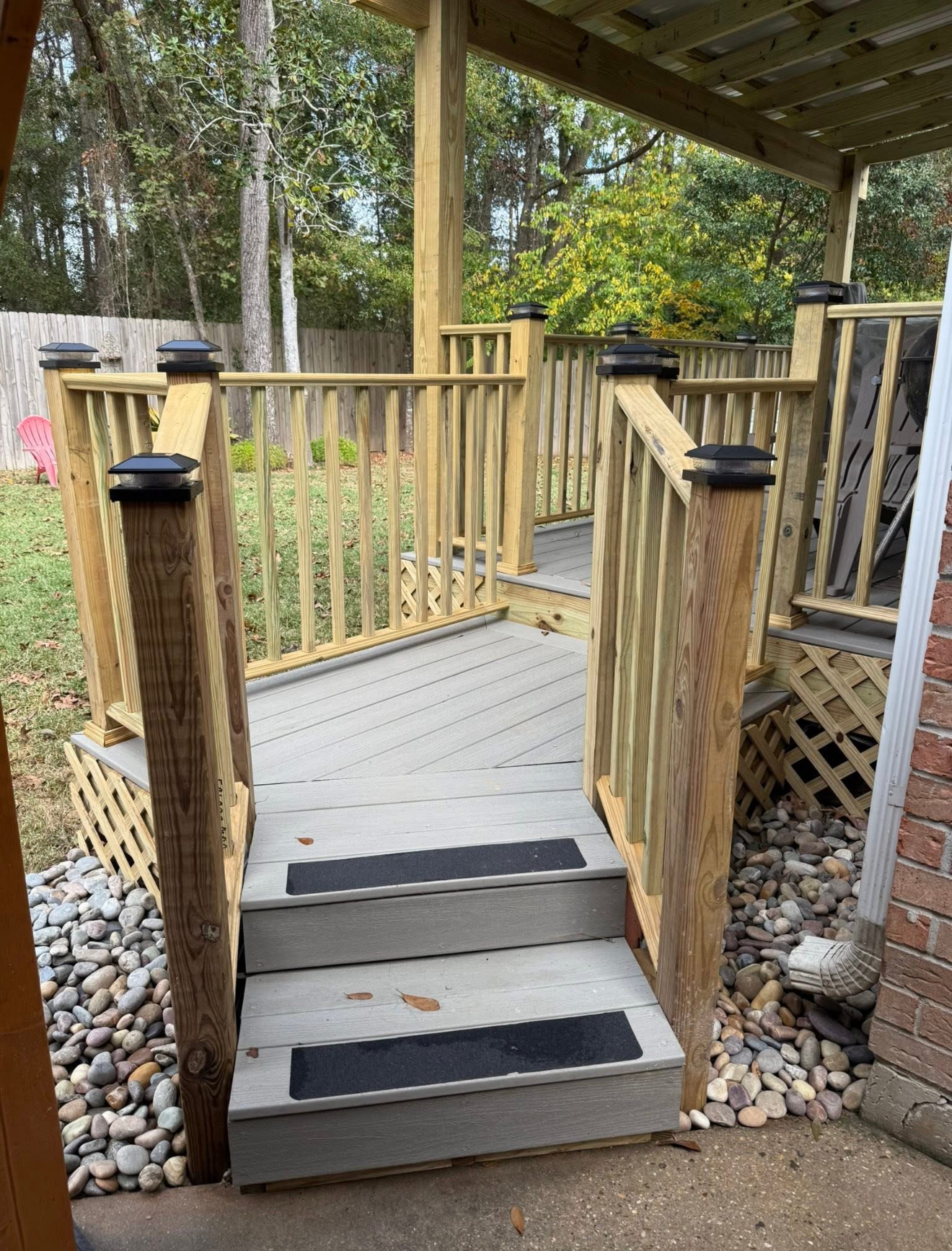 Wooden accessibility ramp with steps, handrails, and black anti-slip strips leading to a deck
