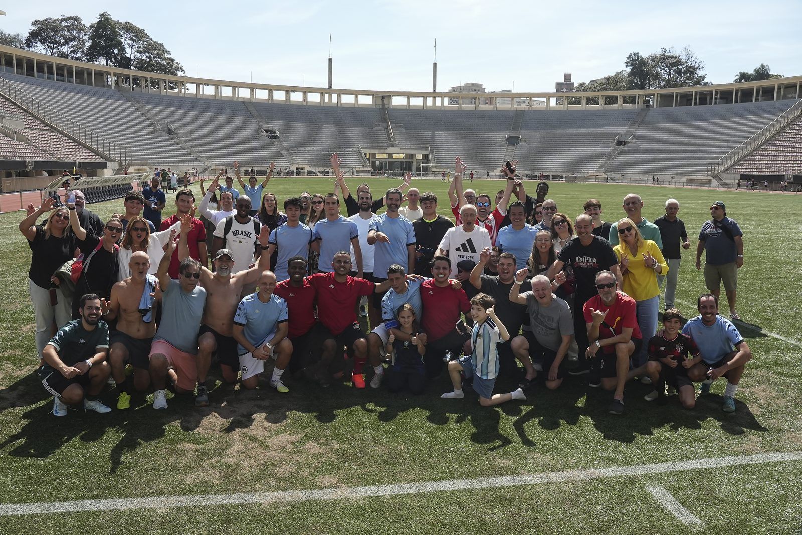 Participantes de um evento Confra FC comemorando no gramado de um estádio