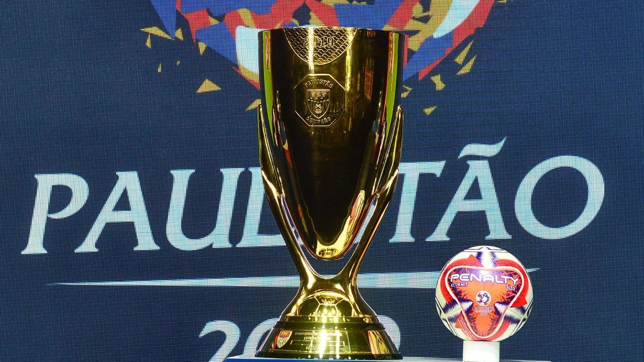 Troféu de ouro e bola de futebol da marca em exposição em frente a um fundo azul escuro com os dizeres