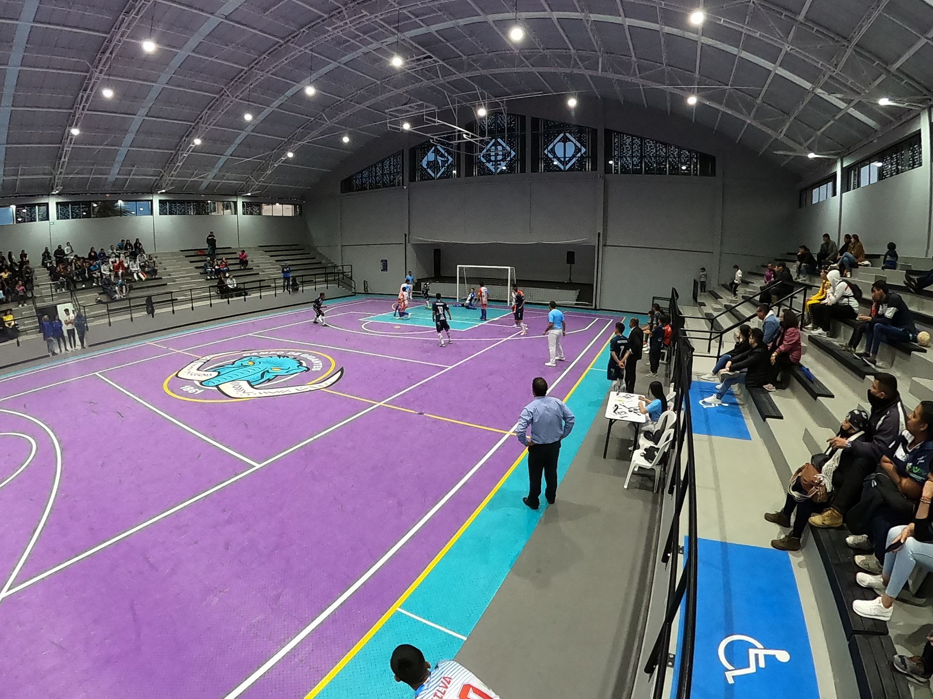 un grupo de personas está viendo un partido de baloncesto en una cancha morada