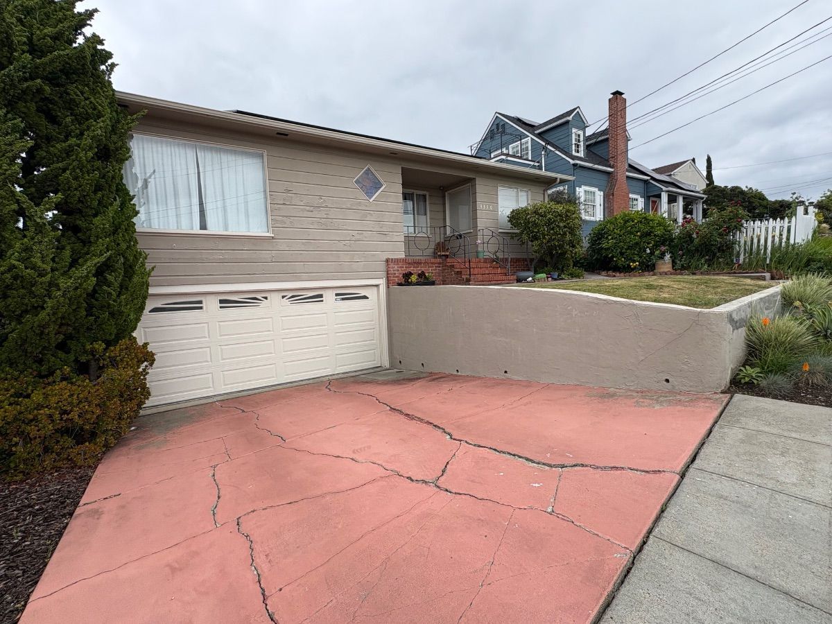 Driveway and garage of a house with a pink concrete surface and beige exterior walls