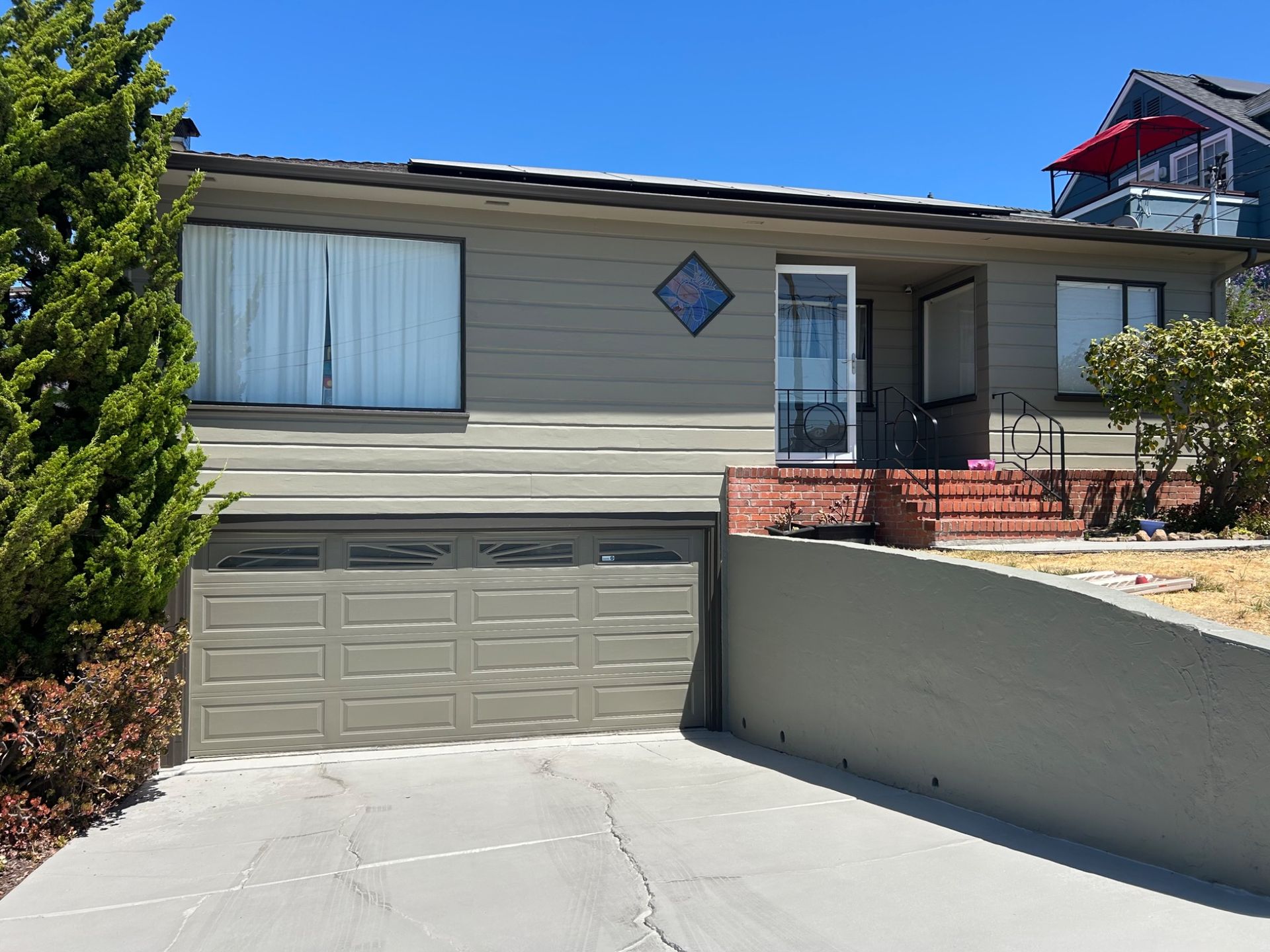 Suburban house exterior with garage, front porch, and a concrete driveway under a clear blue sky