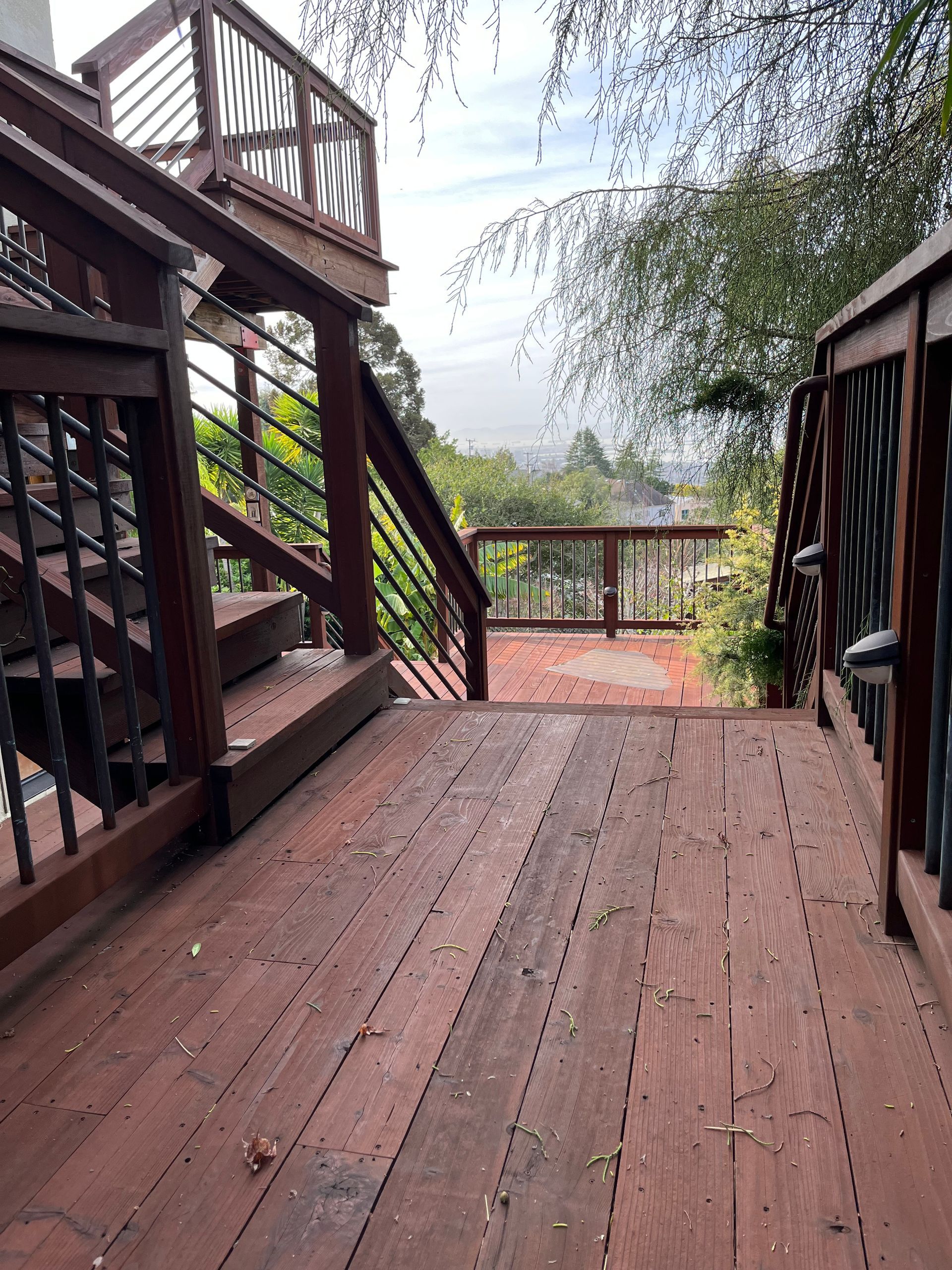 Wooden deck and stairs overlooking a misty forest, with dark railings and wet planks.