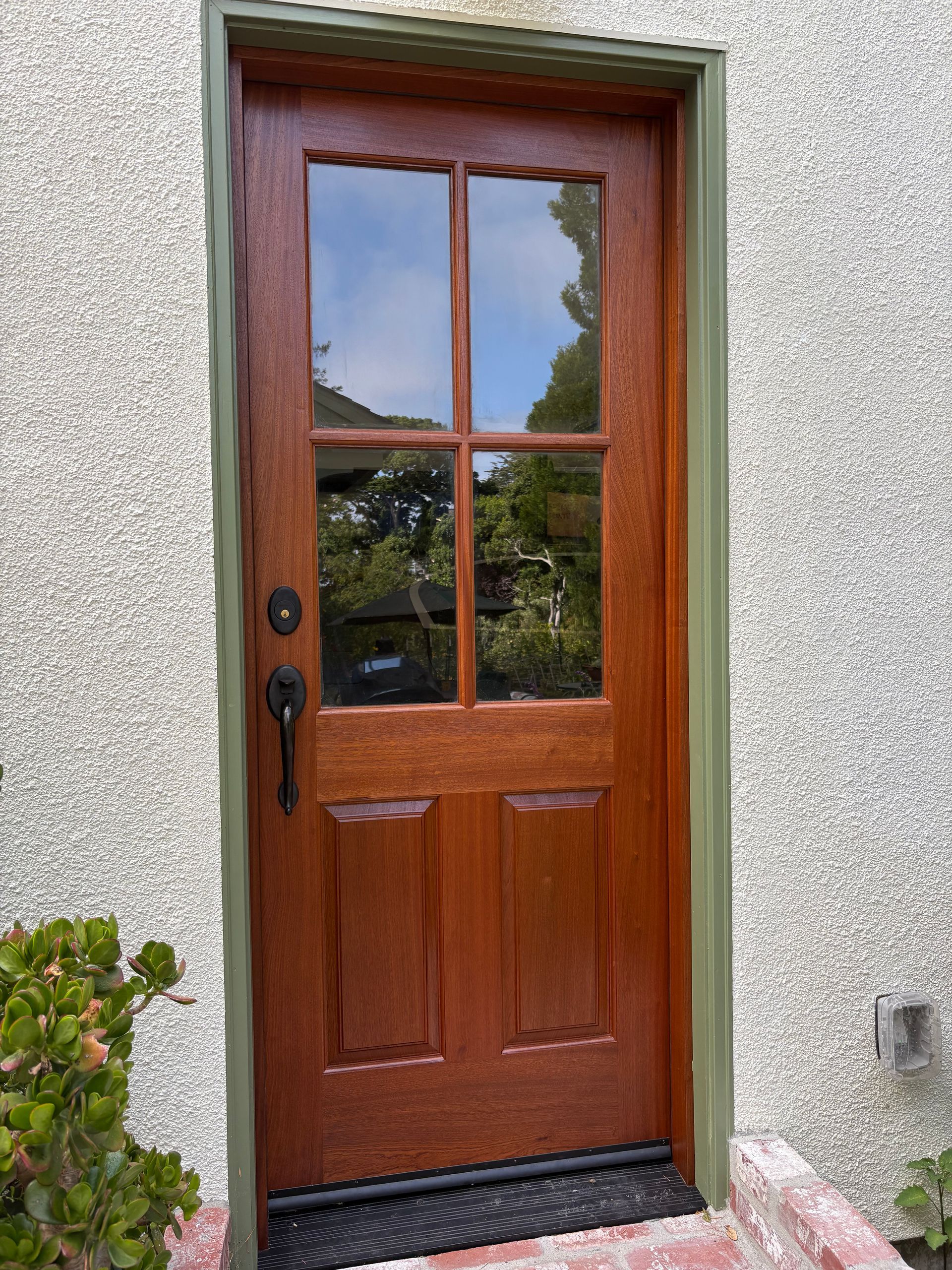 Wooden front door with glass panes set in a stucco exterior wall