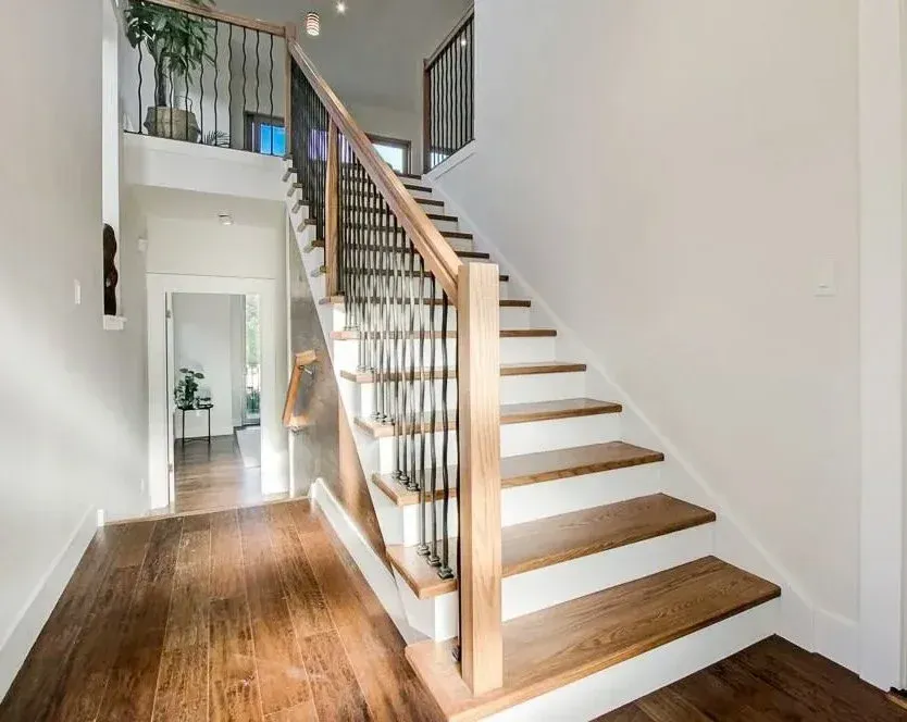 Bright hallway with wooden staircase, white walls, and railing in a modern home interior