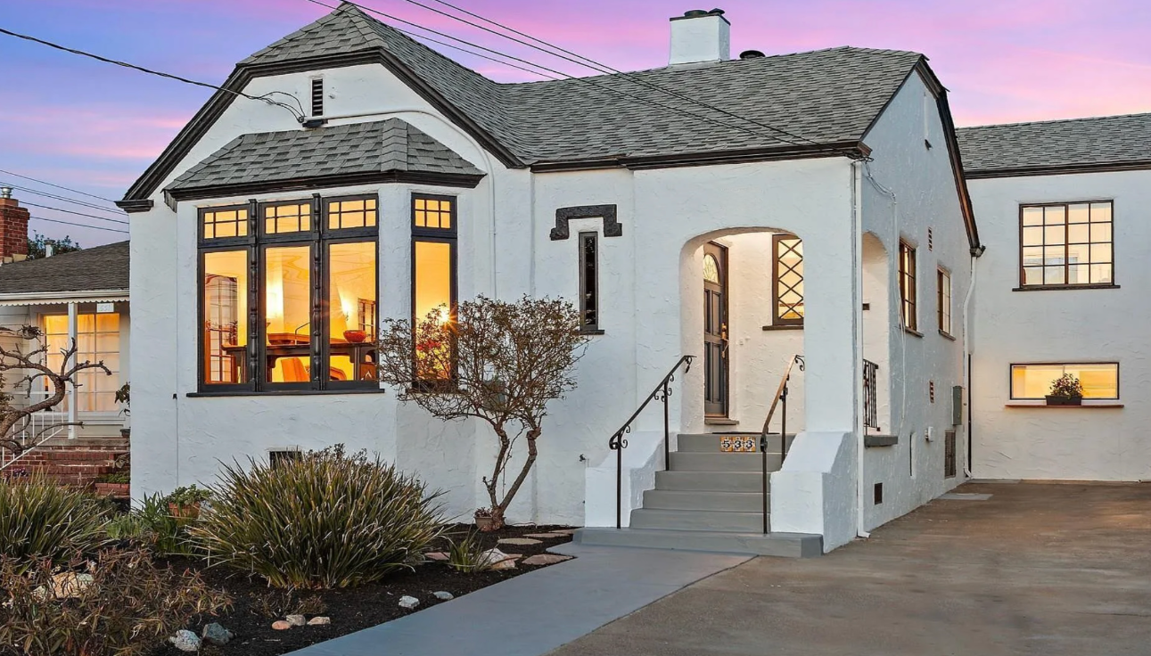Front porch of a gray Victorian house with white trim and decorative columns