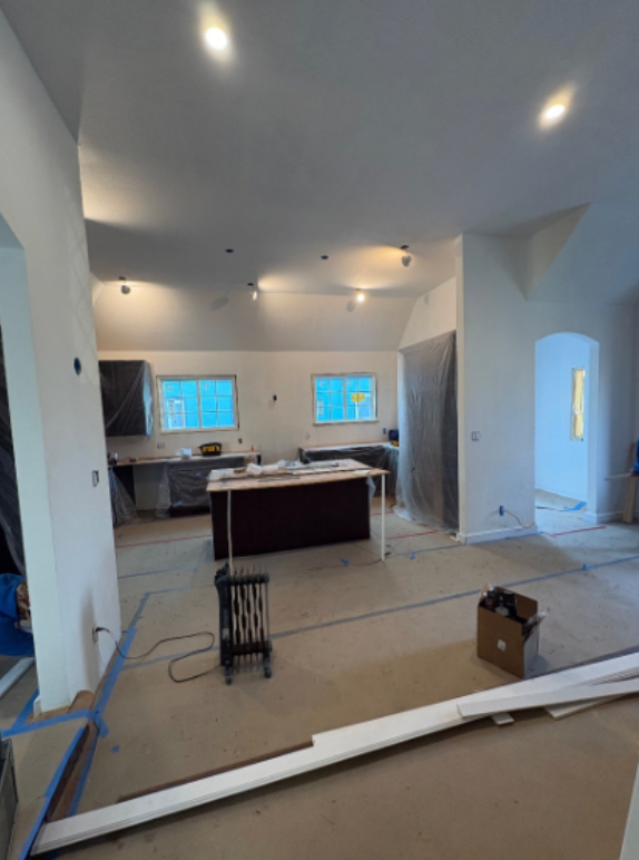 Unfinished kitchen with cabinets, countertops, ceiling lights, and construction materials on the floor.