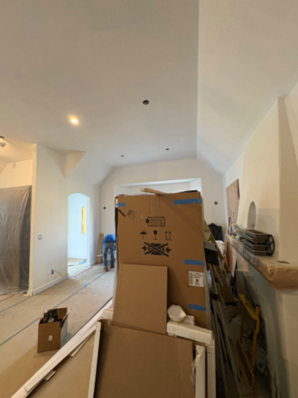 Renovation-cluttered hallway with cardboard boxes, tools, and white walls under a sloped ceiling