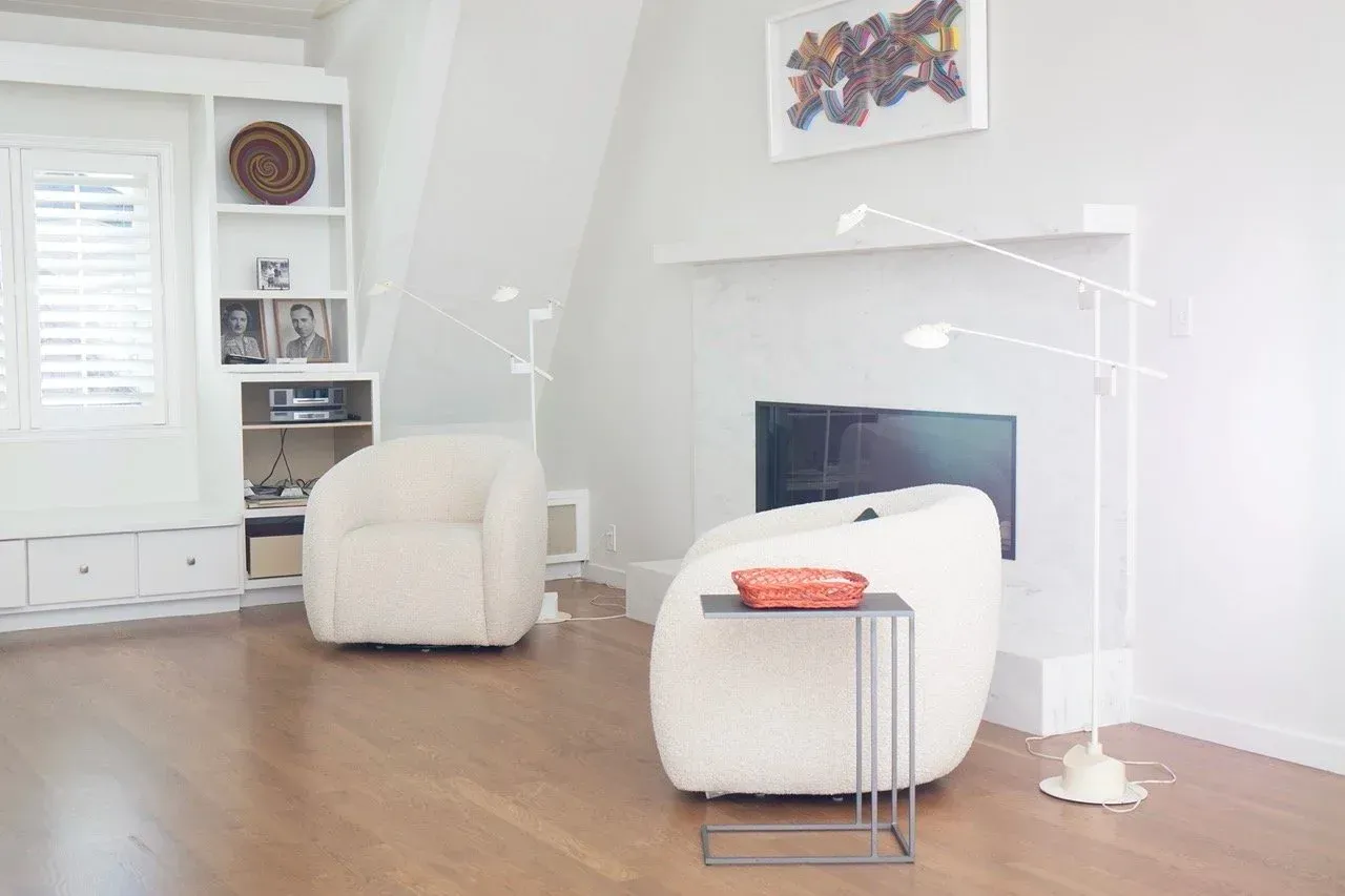 Bright living room with white chairs, fireplace, and wood floor in modern minimalist decor