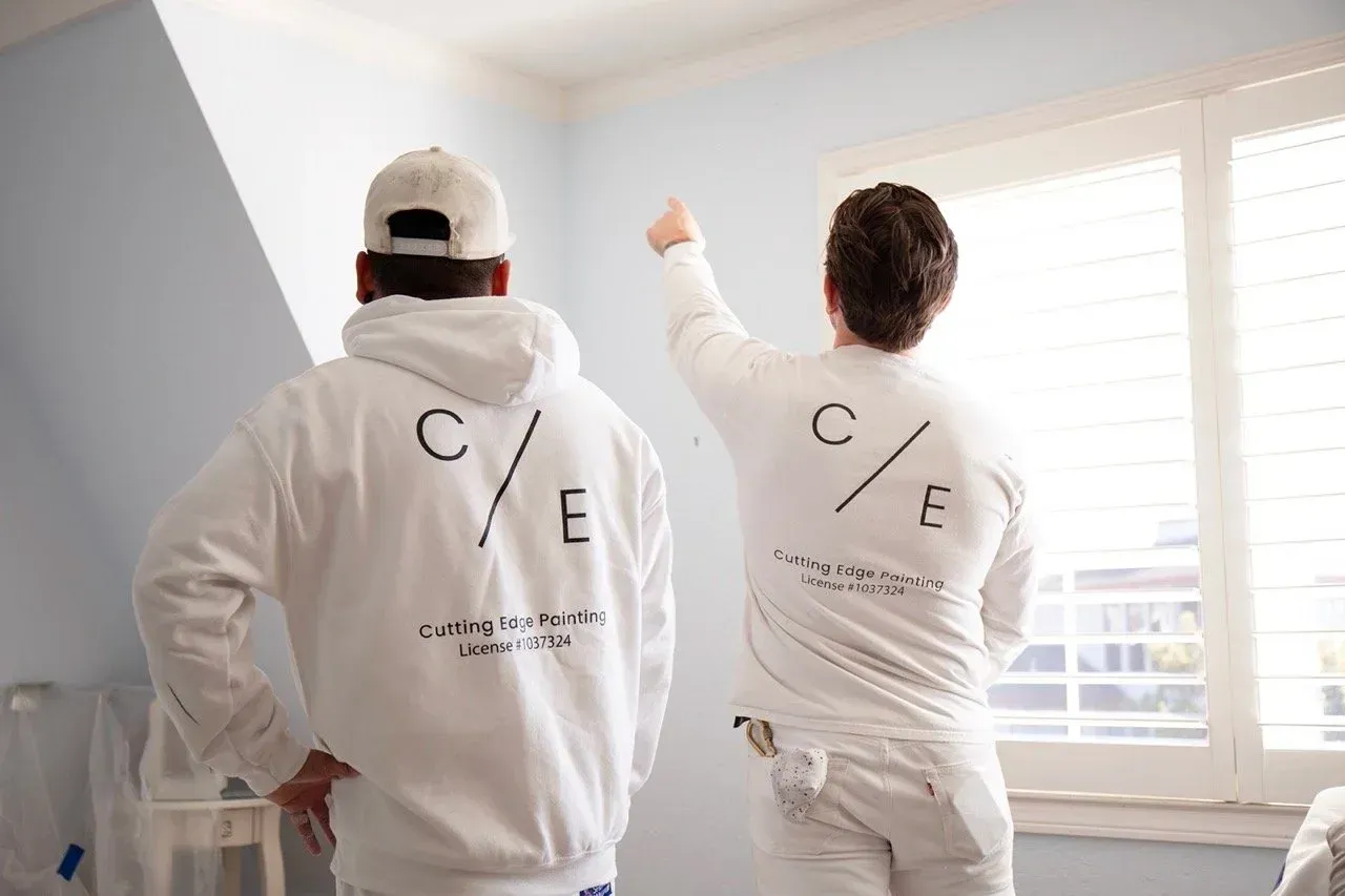 Team of Cutting Edge Painting  in white hoodies working in a bright room by a window