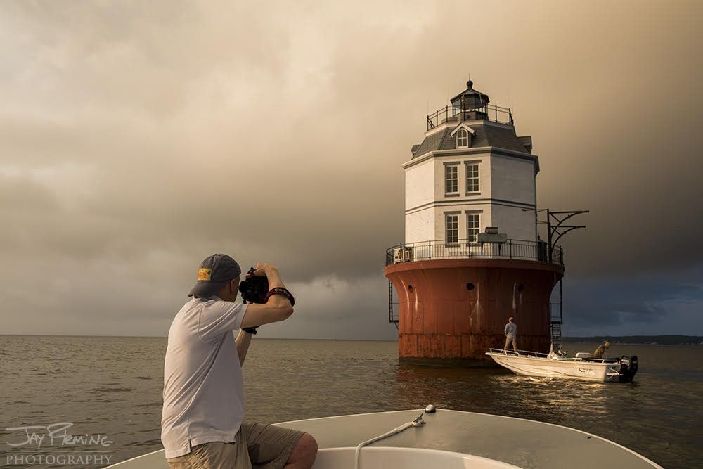 Baltimore Lighthouse at dusk with moon behind it taken by photographer Jay Fleming. Used with permission.