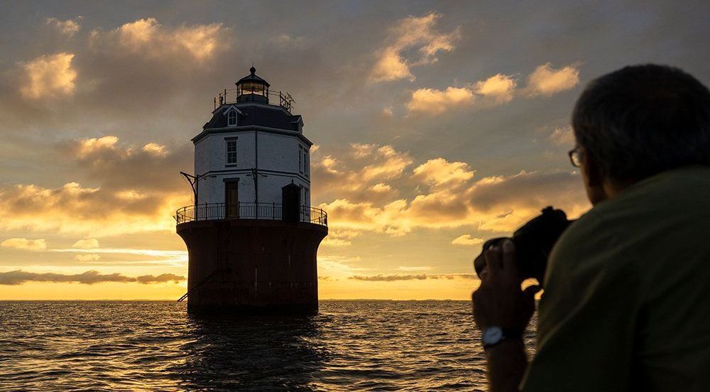 Image of a photography in a boat taking a picture of the Baltimore Light - provided by Jay Fleming Photography