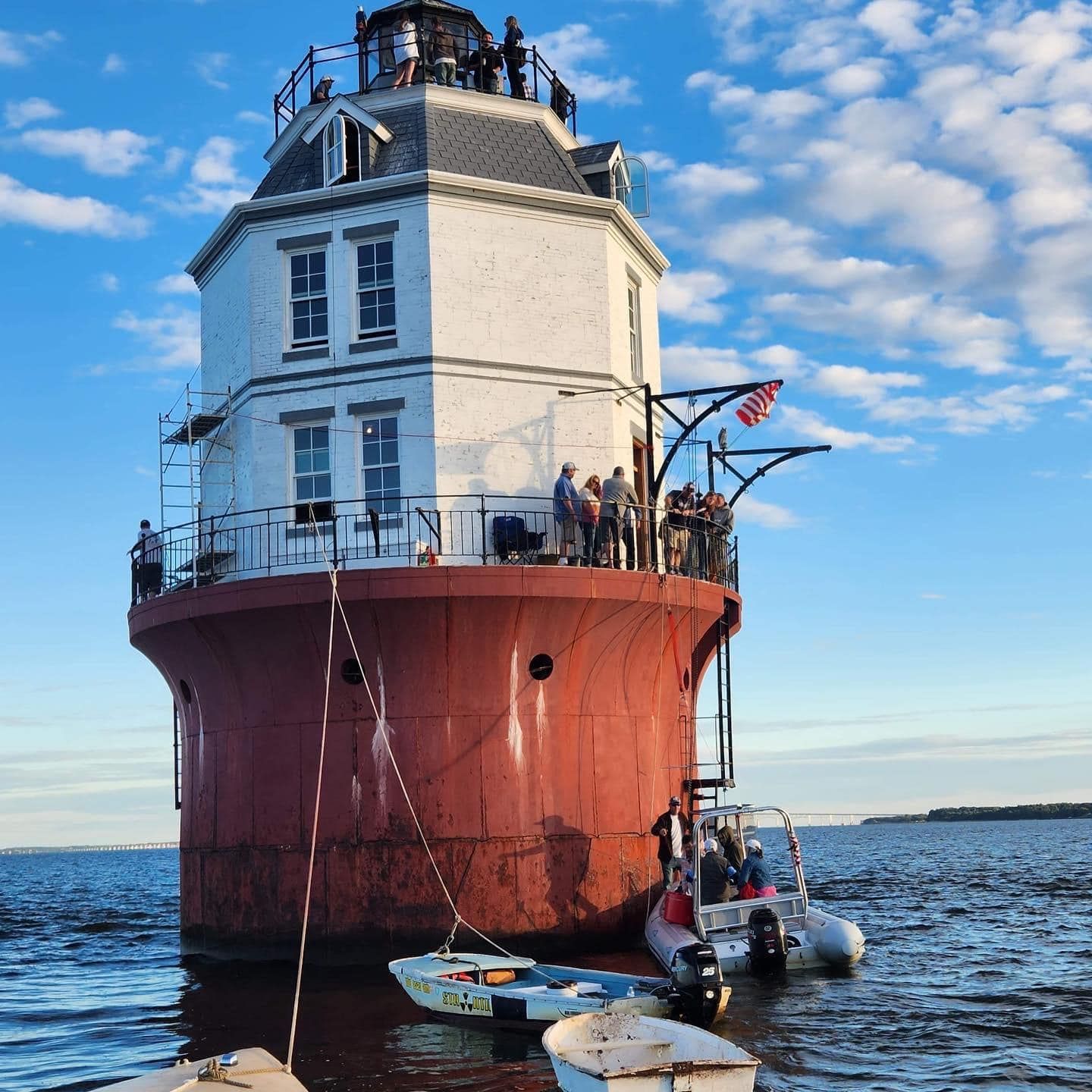 photo of the lighthouse with people on deck and in boats nearby