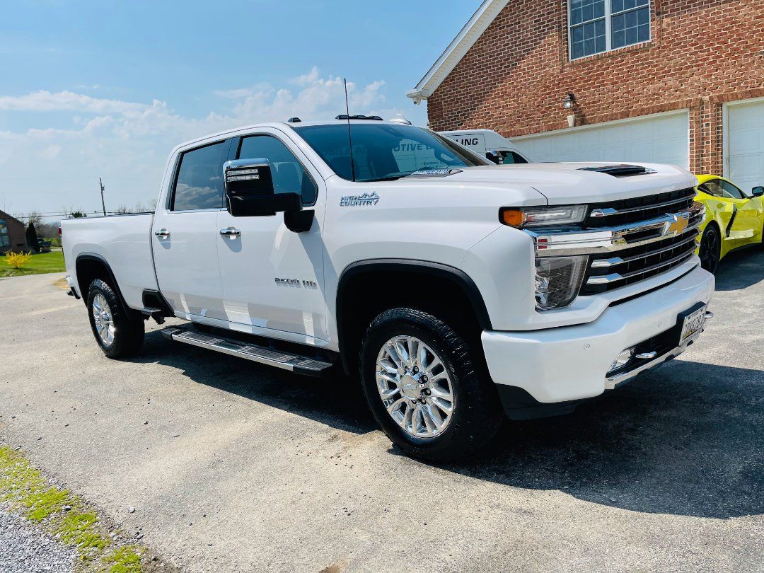 A white truck is parked in front of a brick house.