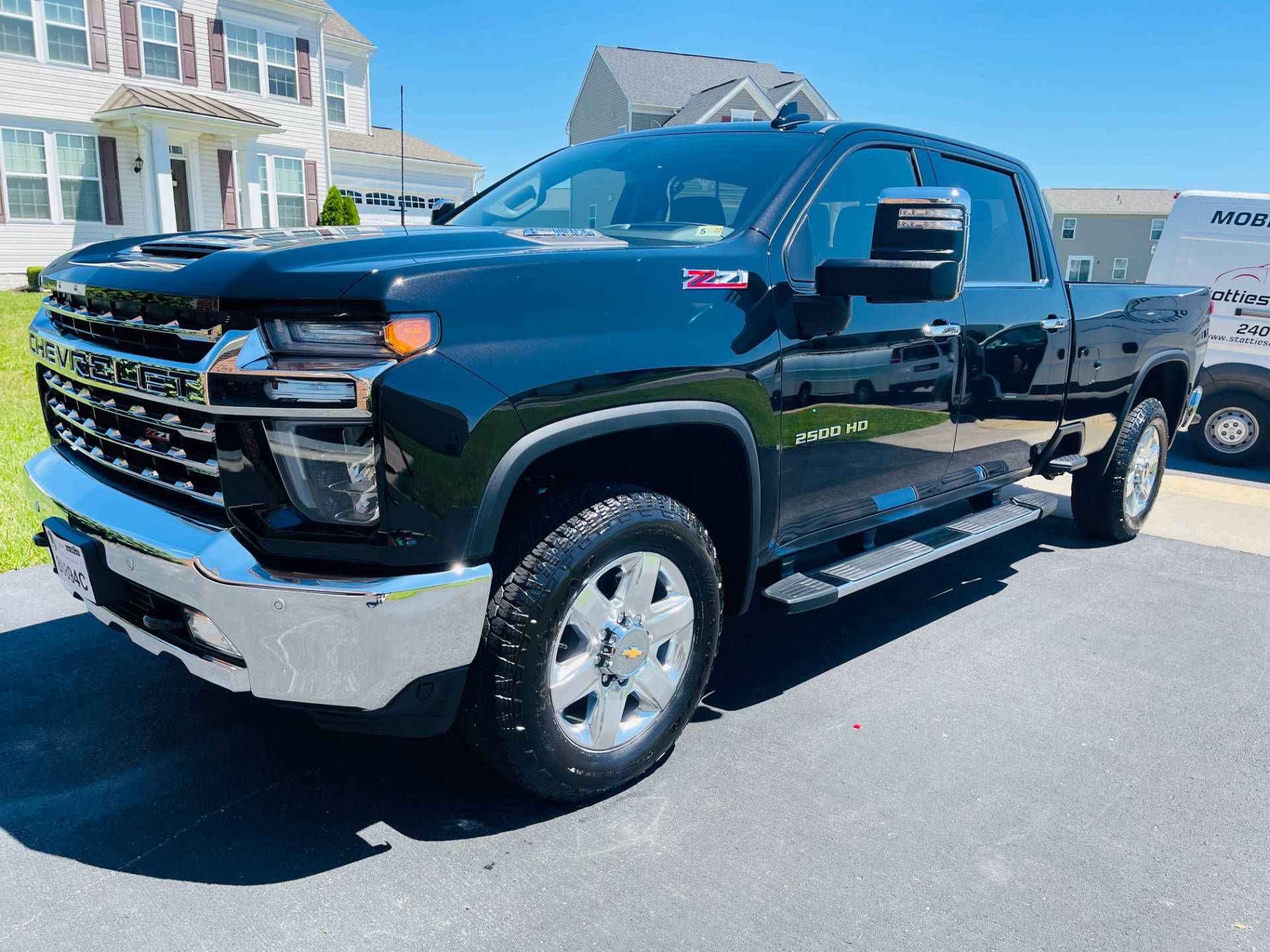 A black truck is parked in a driveway in front of a house.