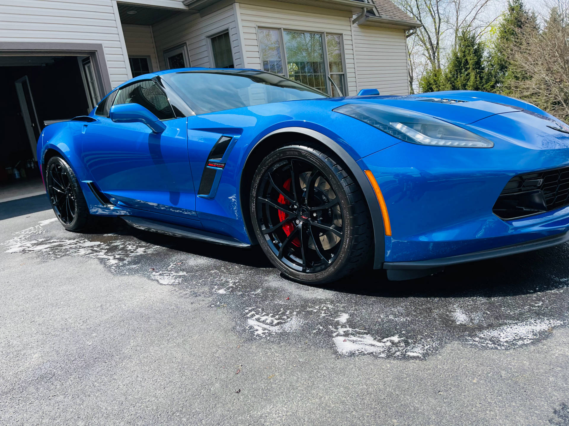 A blue corvette zr1 is parked in a driveway in front of a house.