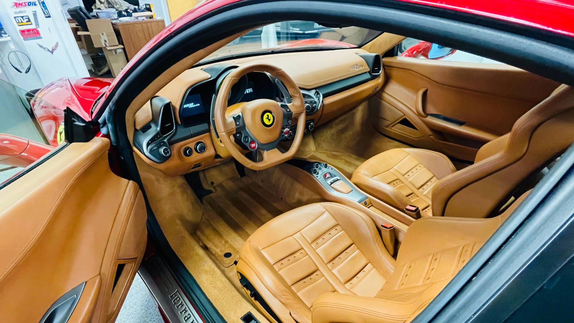 Red Ferrari sports car interior with tan leather seats and dashboard.