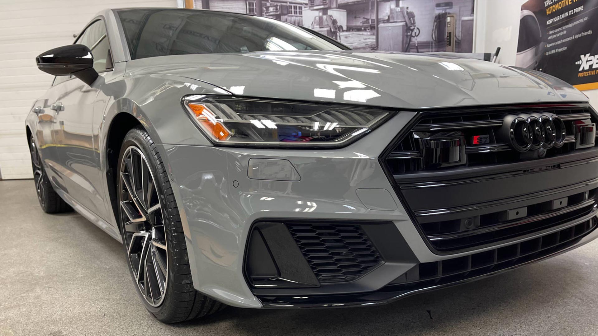 A grey audi a7 rs is parked in a showroom.