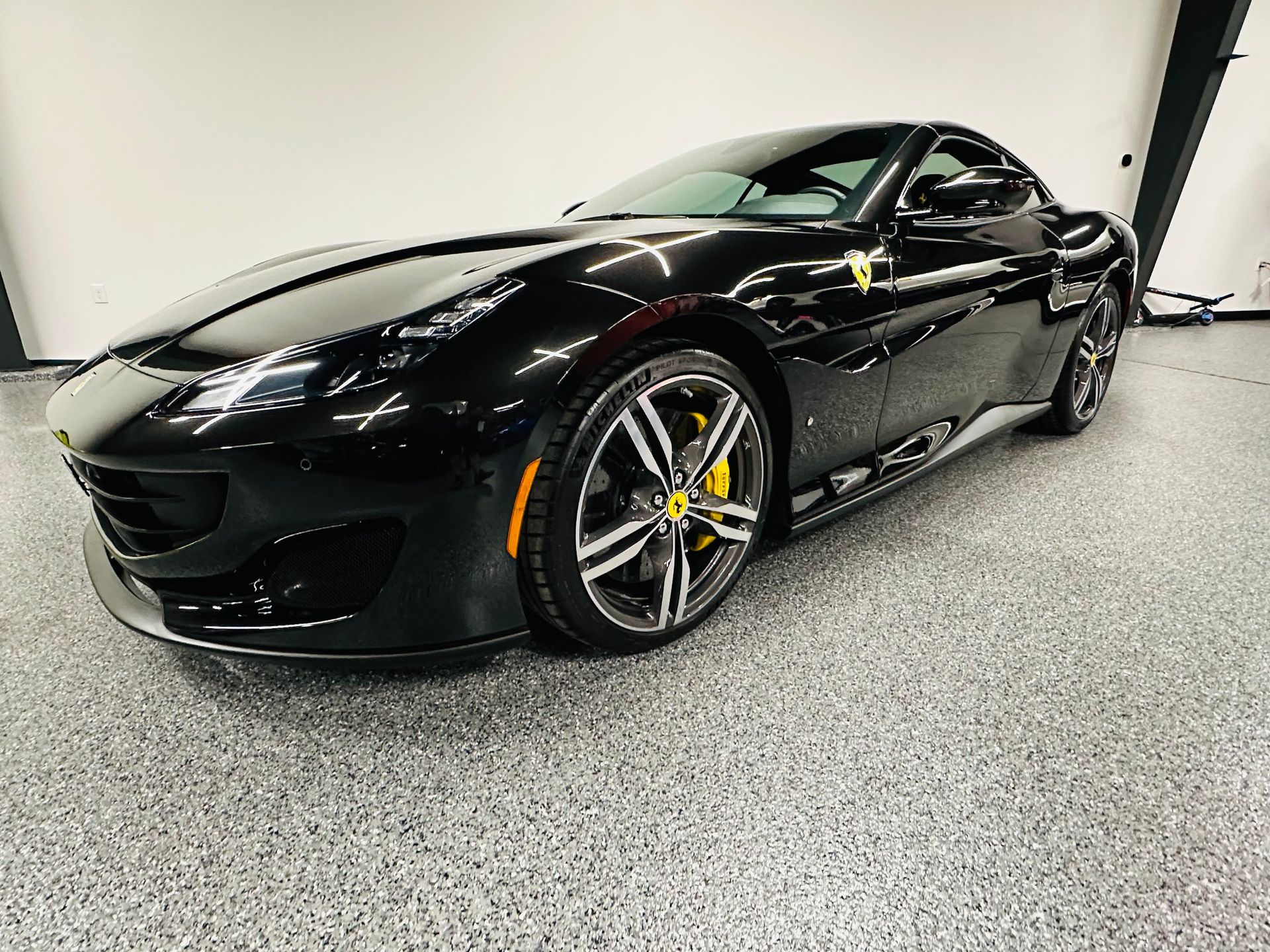 A black sports car is parked in a garage.
