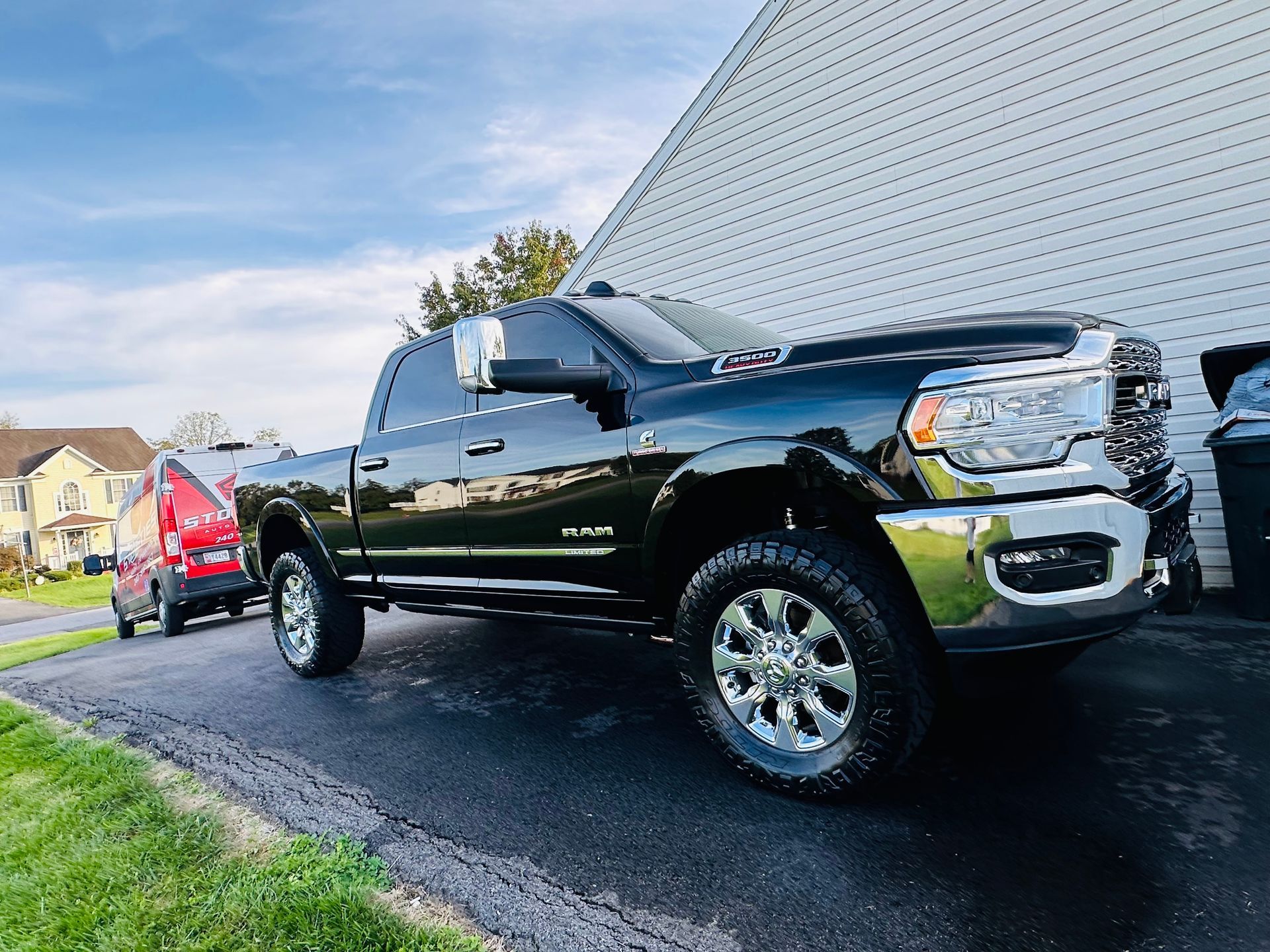 Black Ram pickup truck parked on a driveway next to a white building.
