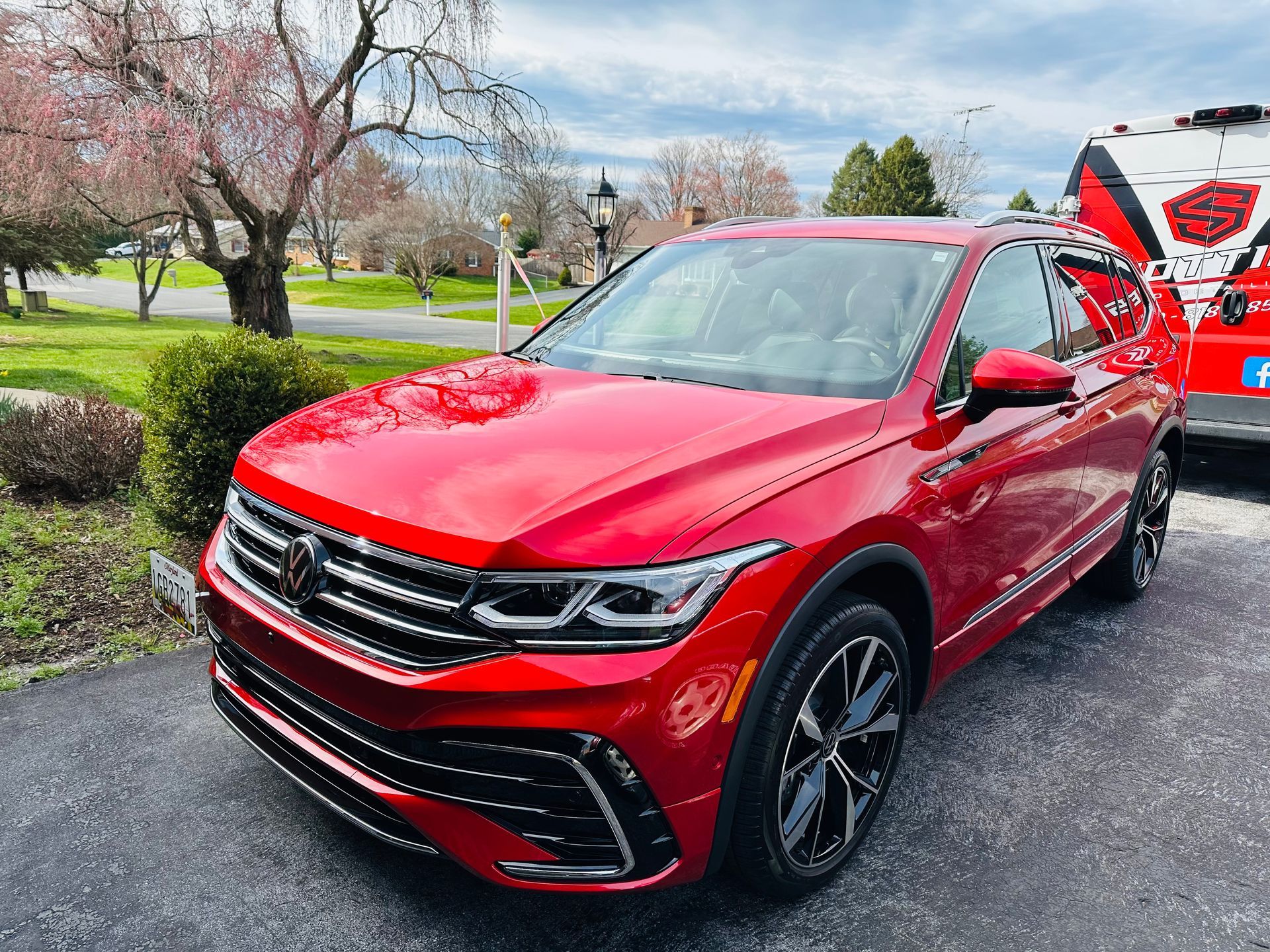 Red Volkswagen Tiguan SUV parked in front of a residential house.