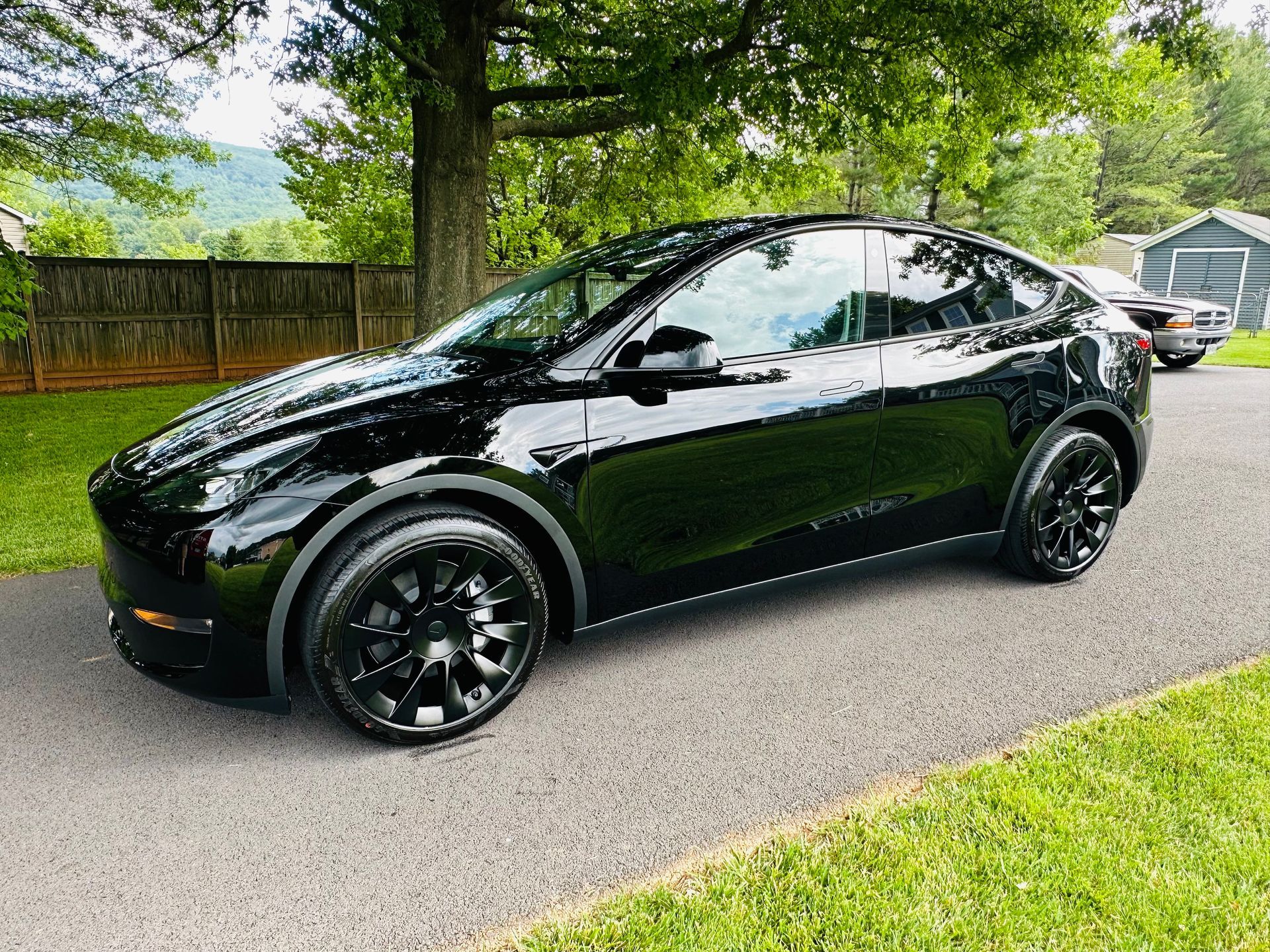 A black tesla model y is parked on the side of a road.
