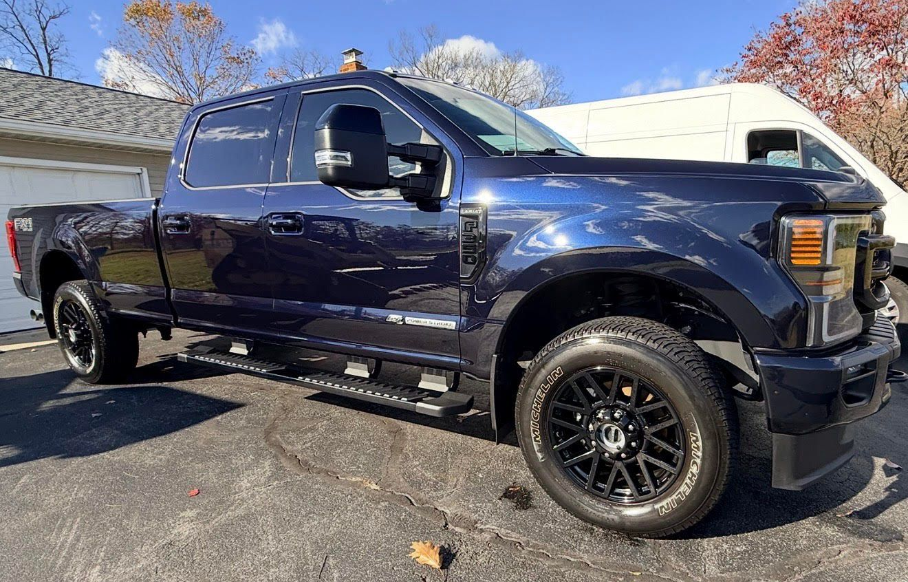 Dark blue Ford pickup truck parked on a driveway. Black wheels and running boards.