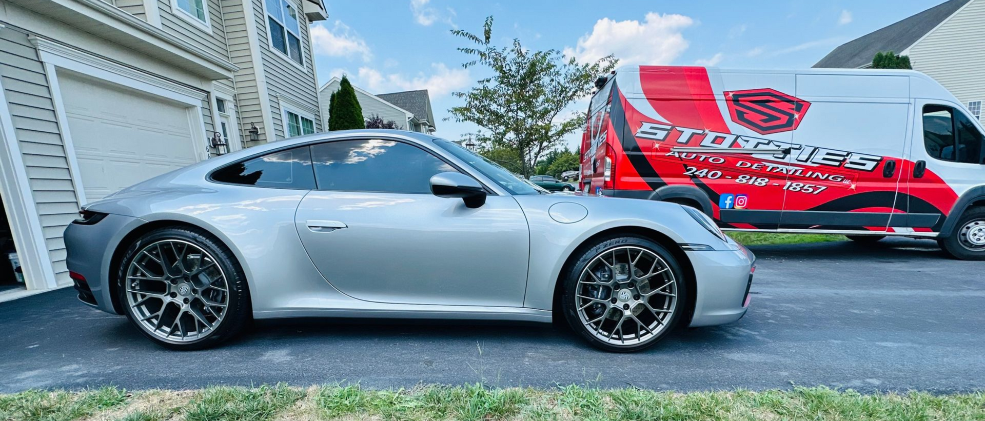 Silver Porsche 911 with ceramic coating service and Stotties Mobile Auto Detailing van in driveway.