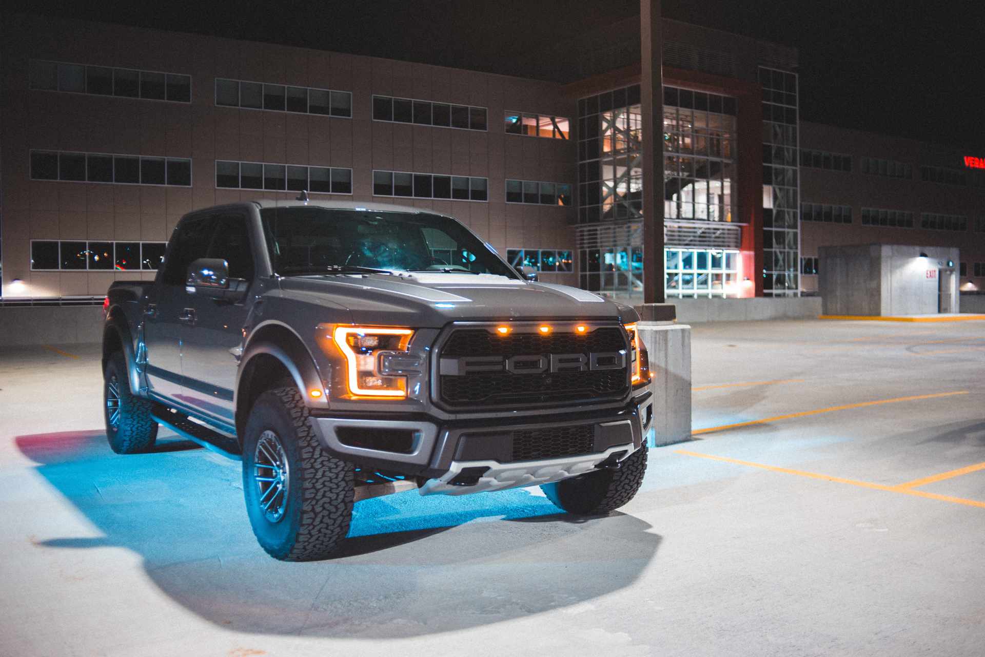 A ford raptor truck is parked in a parking garage at night.