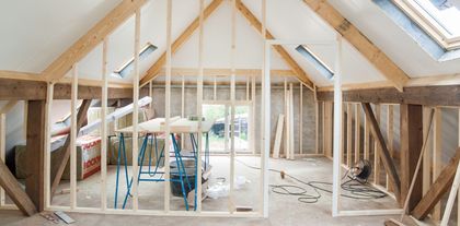 Une pièce est en cours de construction avec des poutres en bois et une lucarne.