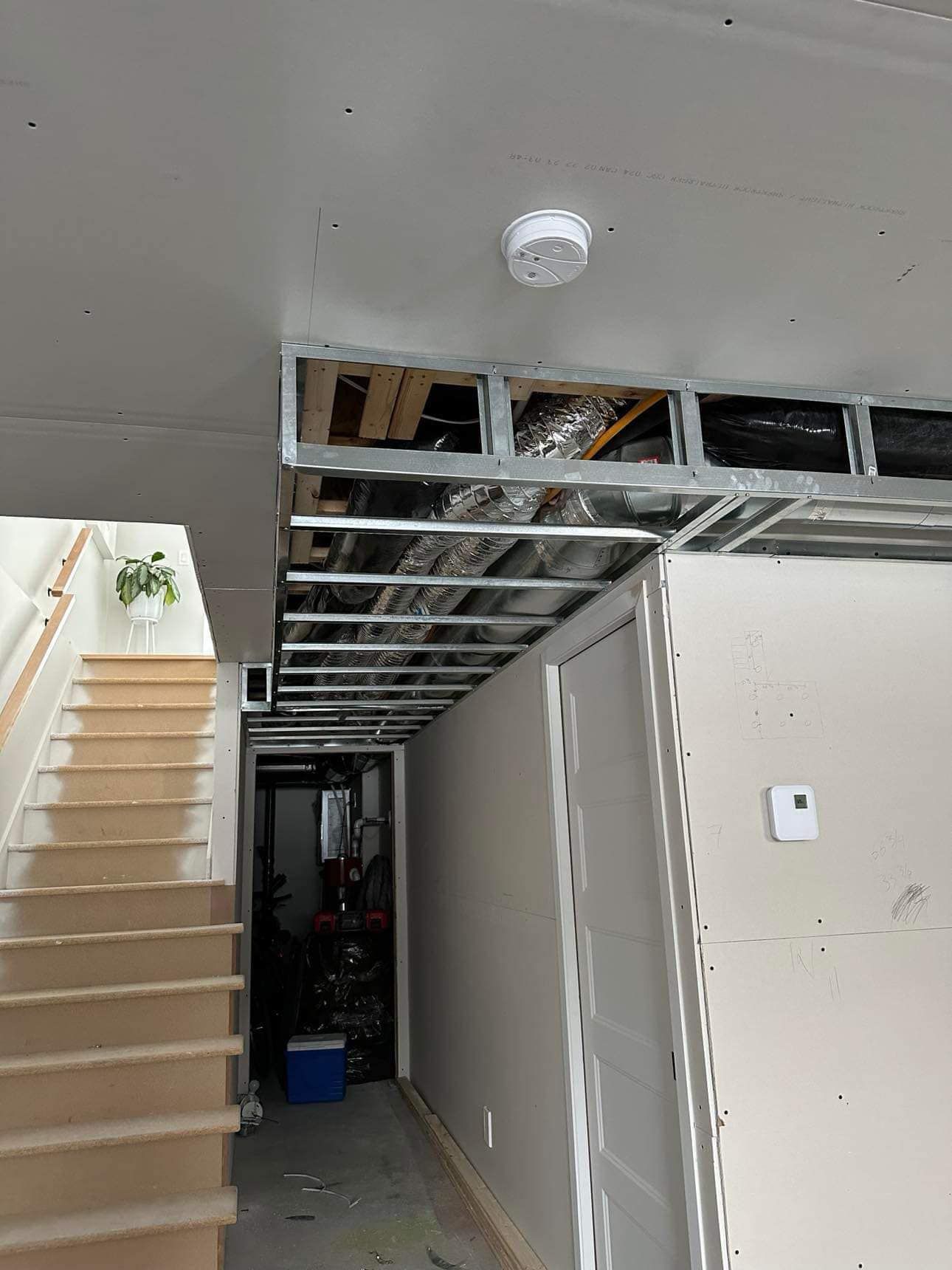 Vue intérieure avec plafond partiellement construit, escalier et couloir.