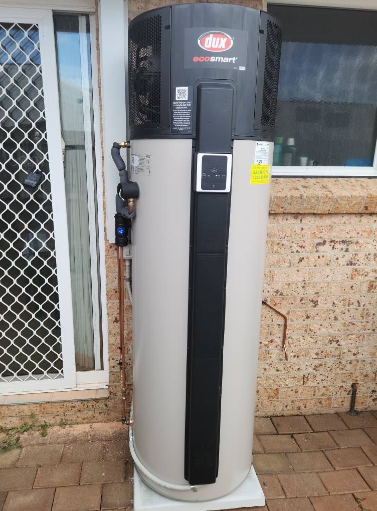 A Dux Ecosmart Heat Pump Hot Water System Stands on a Paved Outdoor — Hot Water Maintenance in Laurieton, NSW