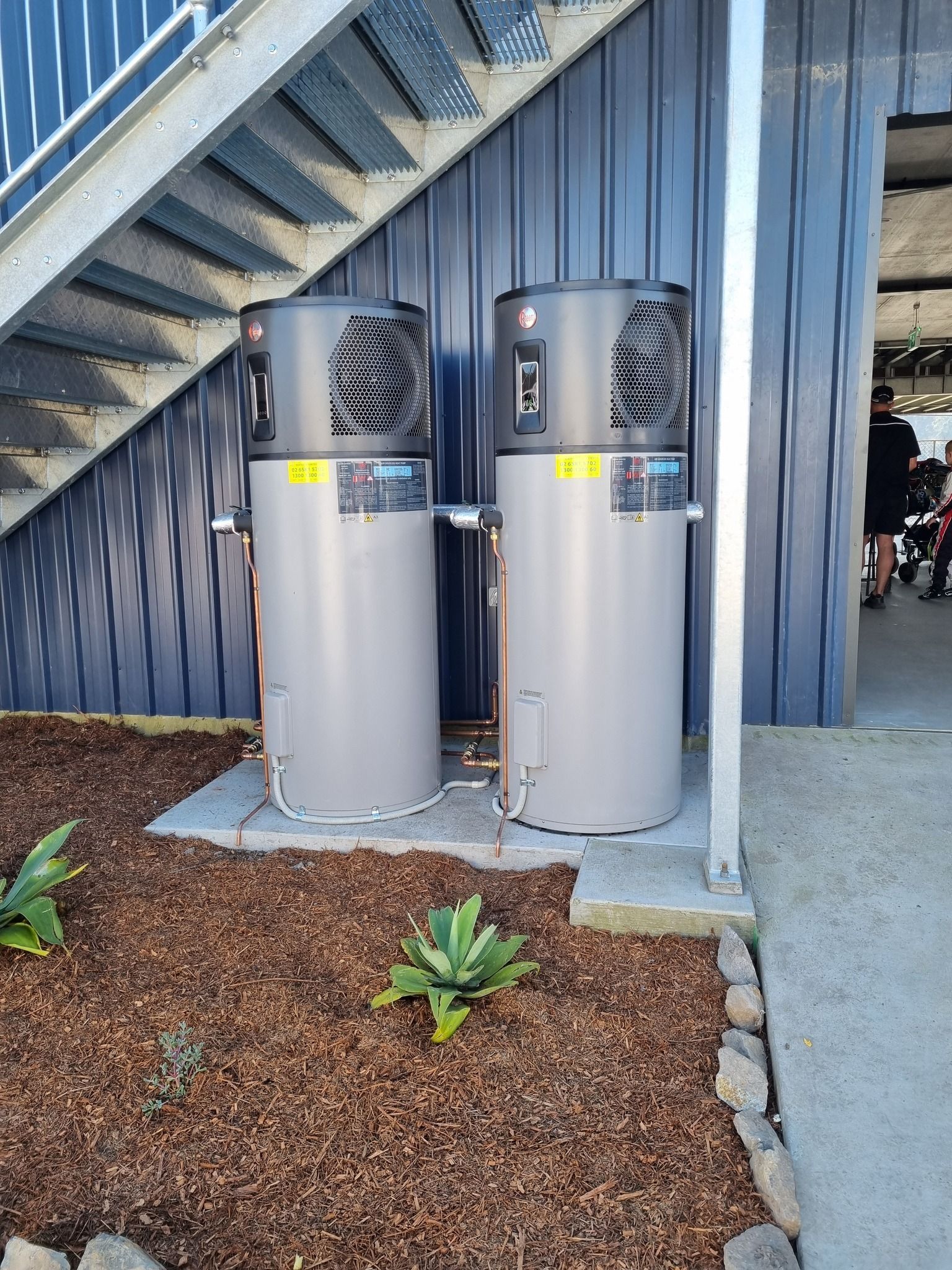 Two Grey Heat Pump Water Heaters Stand Side-by-side — Hot Water Maintenance in Crescent Head, NSW