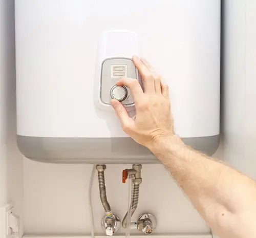 Man Hands Setting the Temperature of Water in Electric Boiler — Hot Water Maintenance in South West Rocks, NSW
