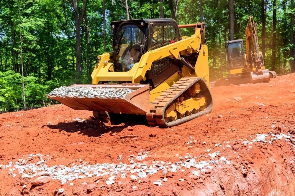 Yellow Track Loader With a Full Bucket, Operating on Red Soil — Rhino Excavator & Bobcat Hire in Brinsmead, QLD