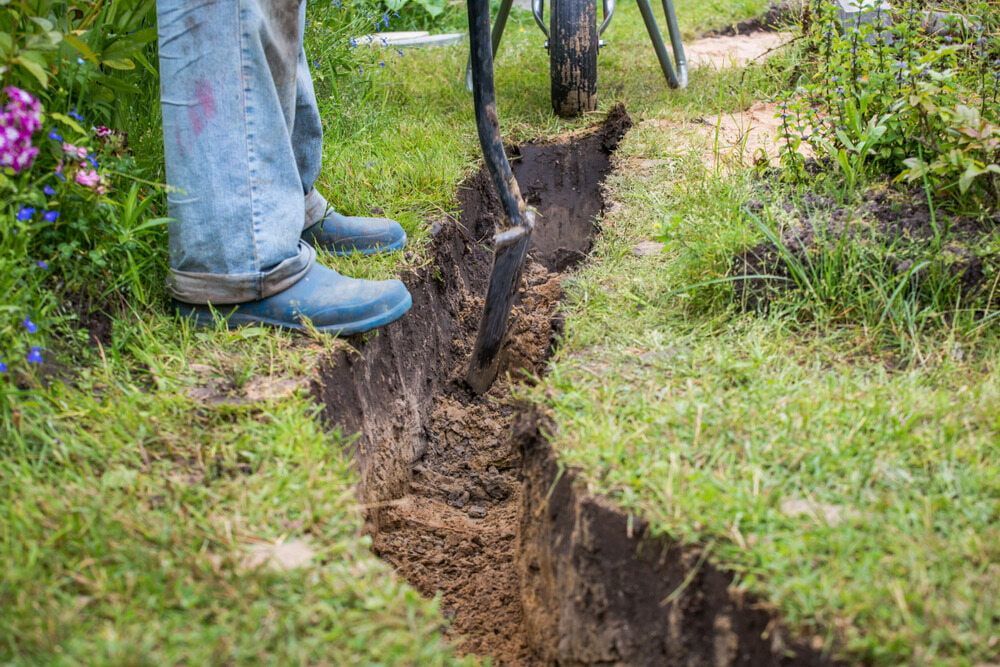 Person Digging a Trench in Grassy Yard With a Shovel — Rhino Excavator & Bobcat Hire in Redlynch, QLD 