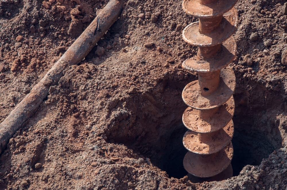 Auger Drilling a Hole in Brown Soil — Rhino Excavator & Bobcat Hire in Trinity Beach, QLD